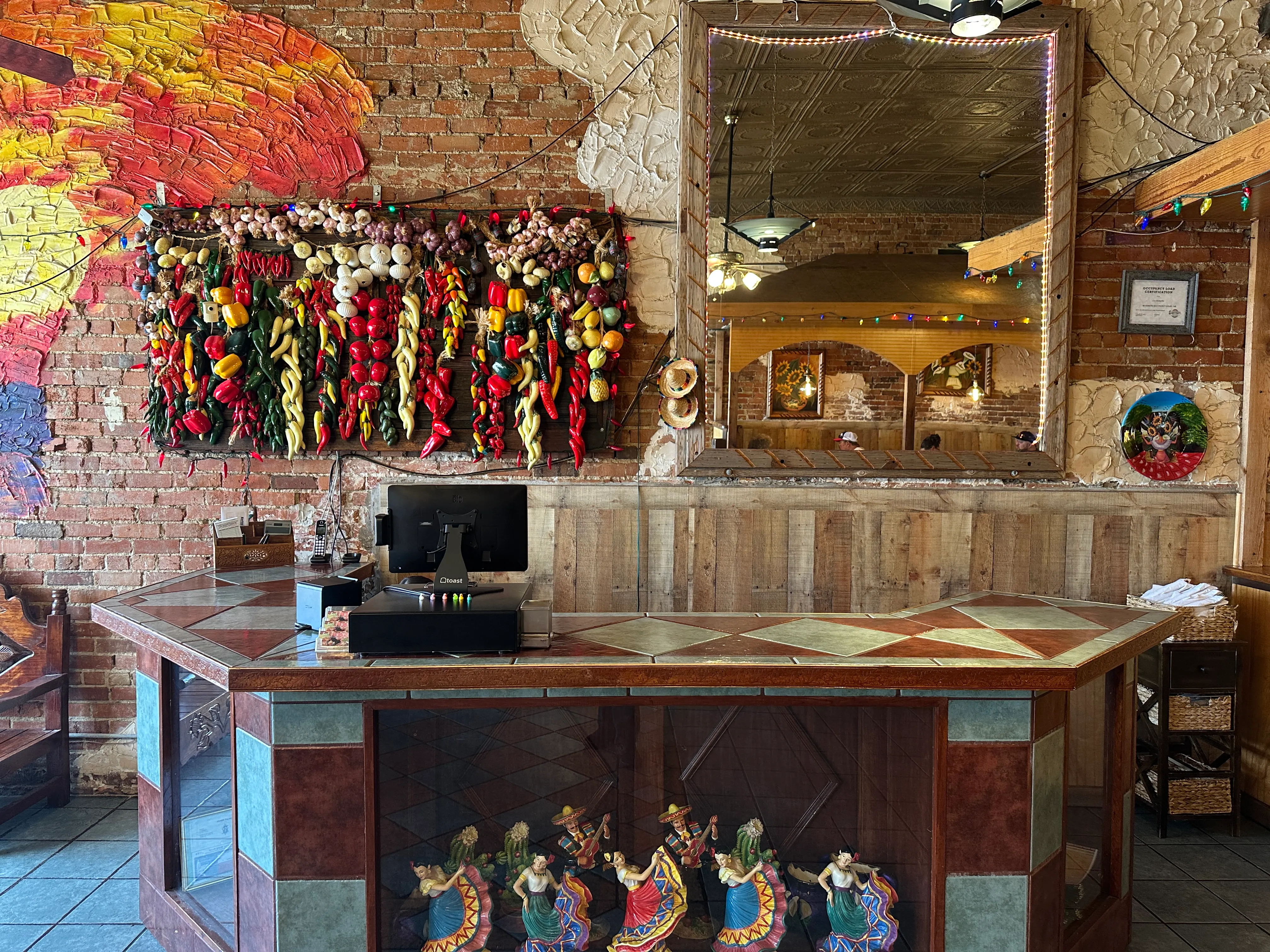 Warm, rustic front of house at Los Mariachis Tex-Mex gainesville with exposed brick walls, hand-carved decoration, and traditional Mexican décor